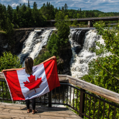 Woman holding Canadian flag near a waterfall